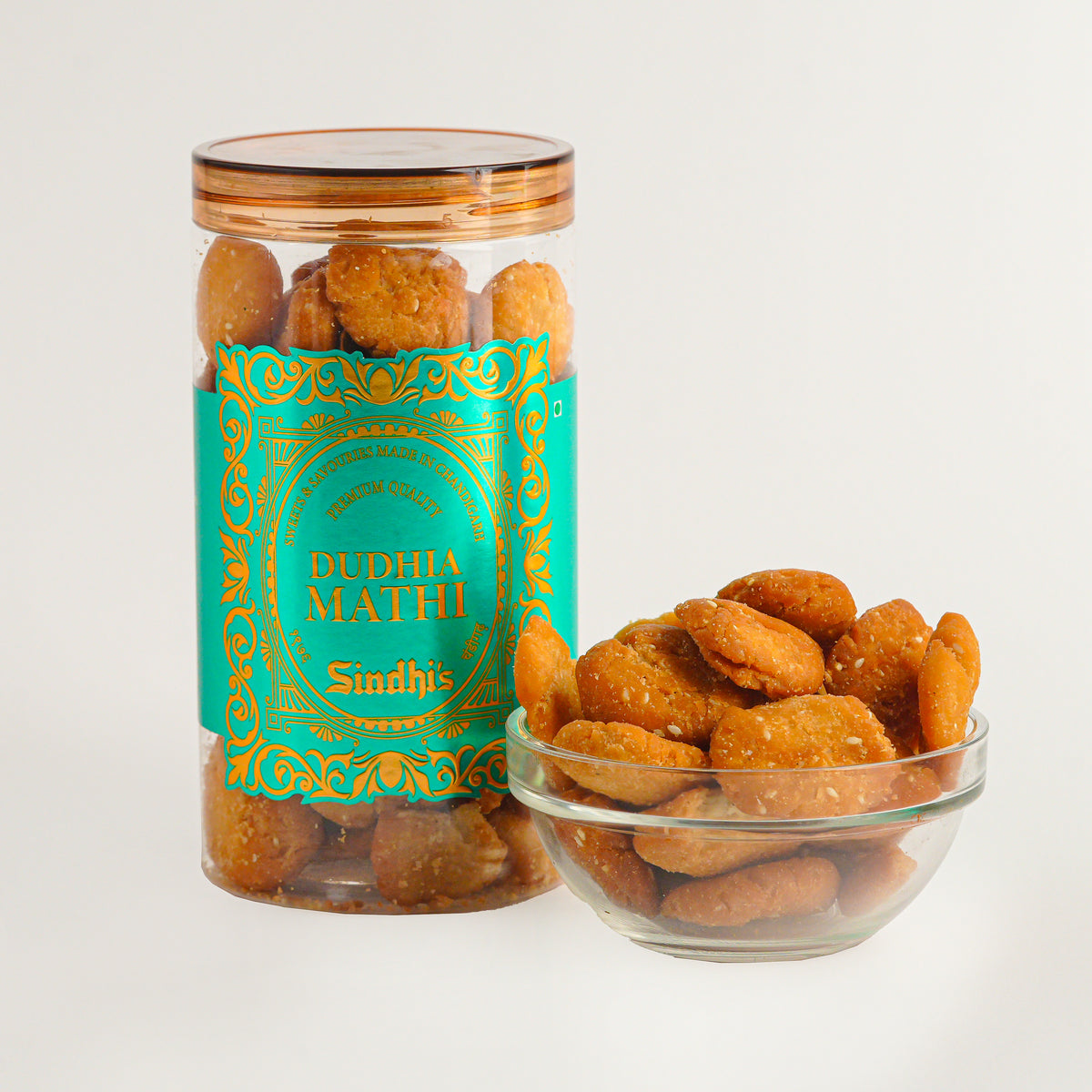 Jar and bowl of Dudhia Mathi Sindhi snacks on a white background