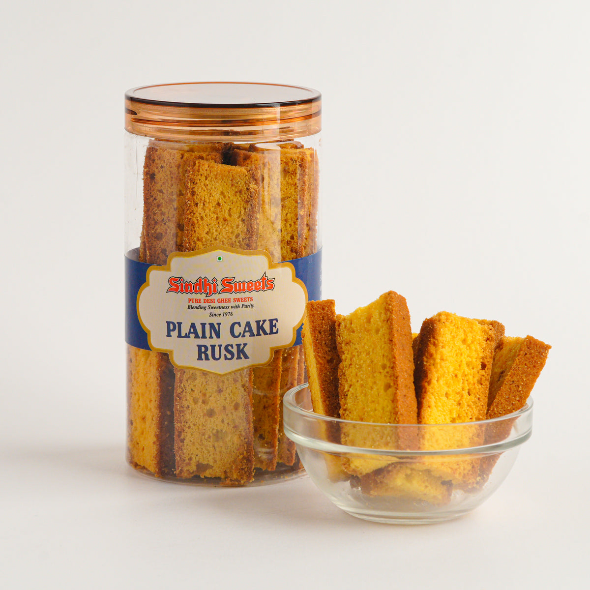Jar of Sindhi Sweets Plain Cake Rusk with a bowl of rusk pieces on a white background