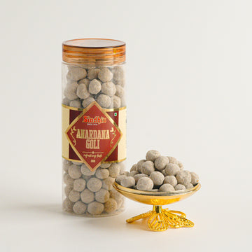 Jar of 'Amarjana Goli' with a decorative bowl filled with the product on a white background
