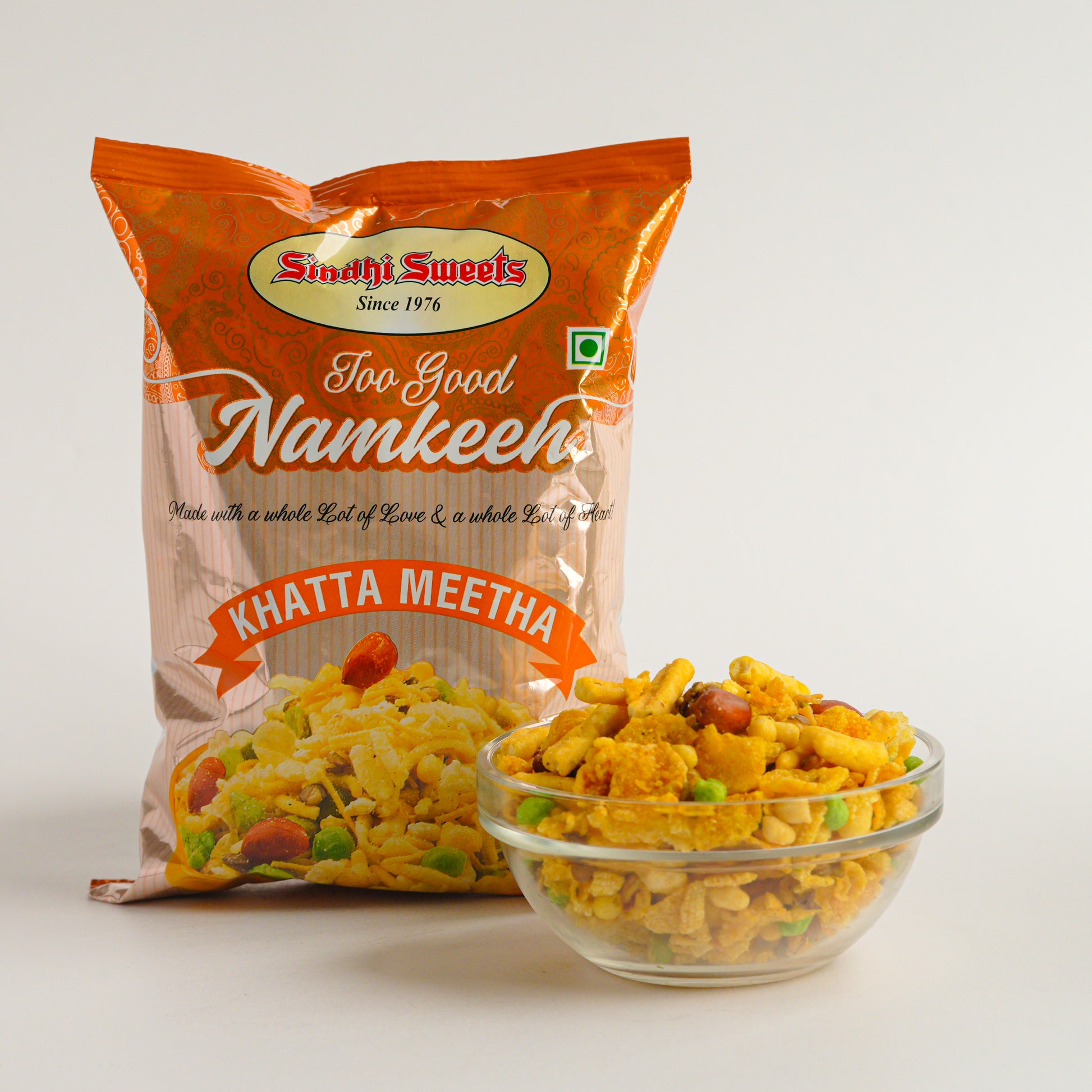 Packaged snack with 'Sindhi Sweets' branding and a bowl of snack in front on a white background