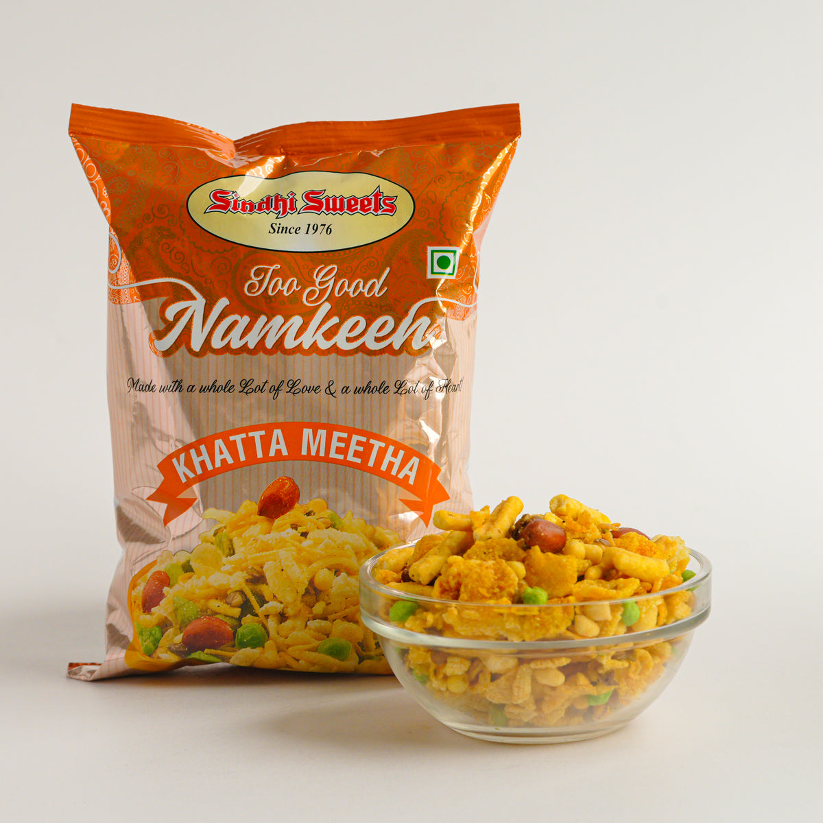 Packaged snack with 'Sindhi Sweets' branding and a bowl of snack in front on a white background