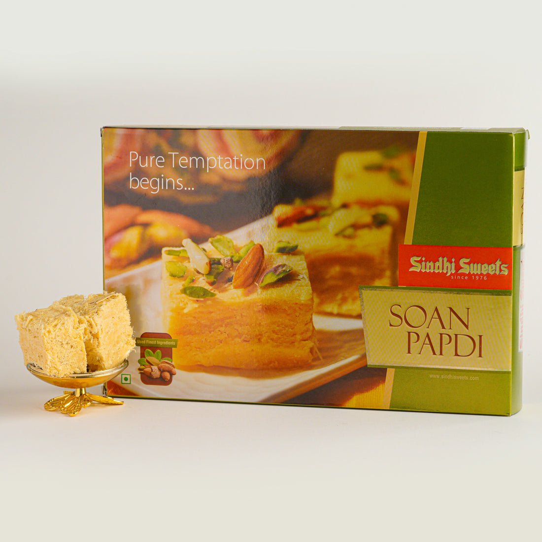 Box of Sindhi Sweets Soan Papdi with a piece of the dessert on a white background