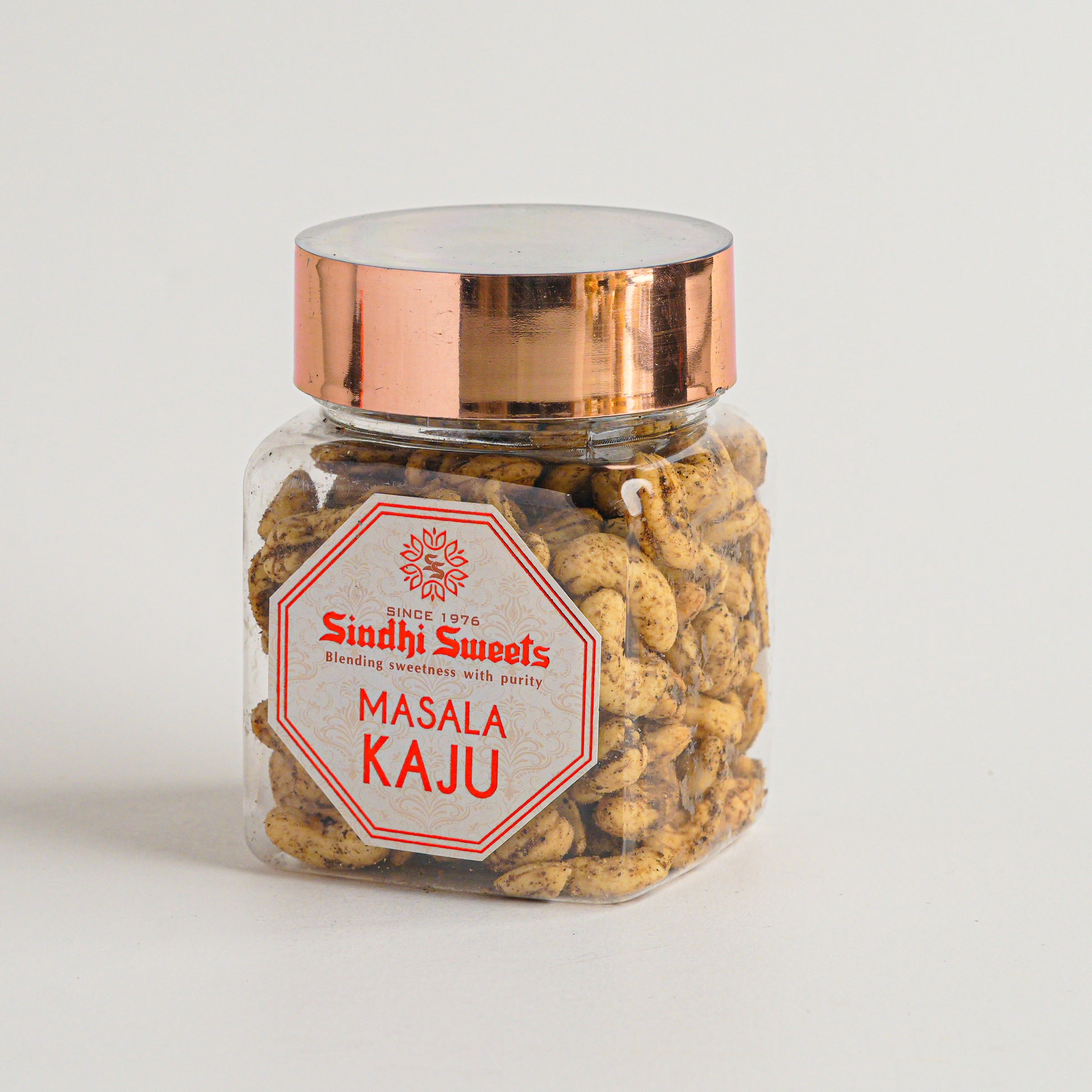Jar of 'Masala Kaju' with a copper lid on a light gray background