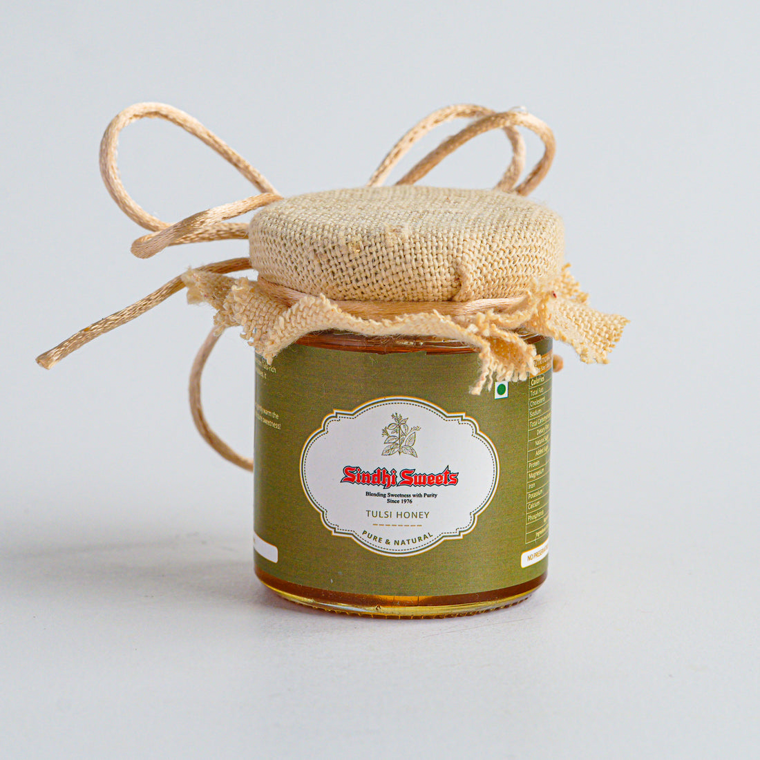 Jar of honey with a decorative string on a light gray background