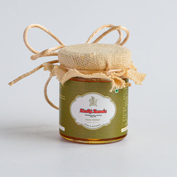 Jar of honey with a decorative string on a light gray background