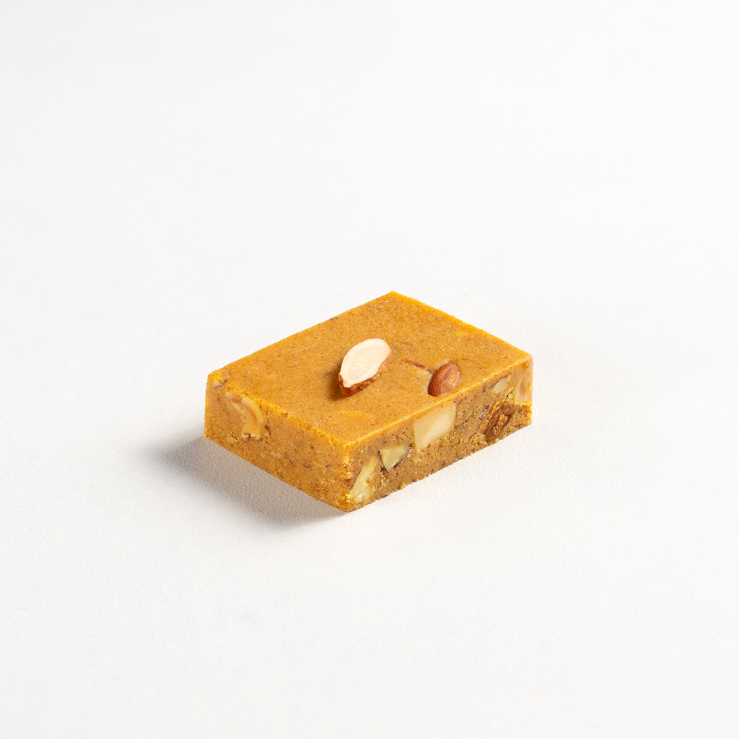 Rectangular piece of orange-colored nougat with nuts on a white background