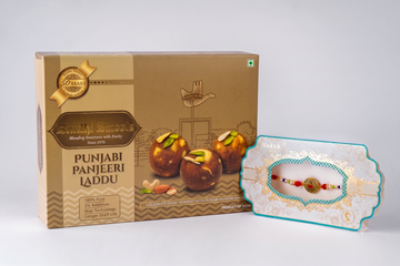 A boxed gift set of Punjabi Panjeeri Laddu sweets next to a packaged rakhi with a decorative thread and a small laddu, photographed on a clean light gray studio background.
