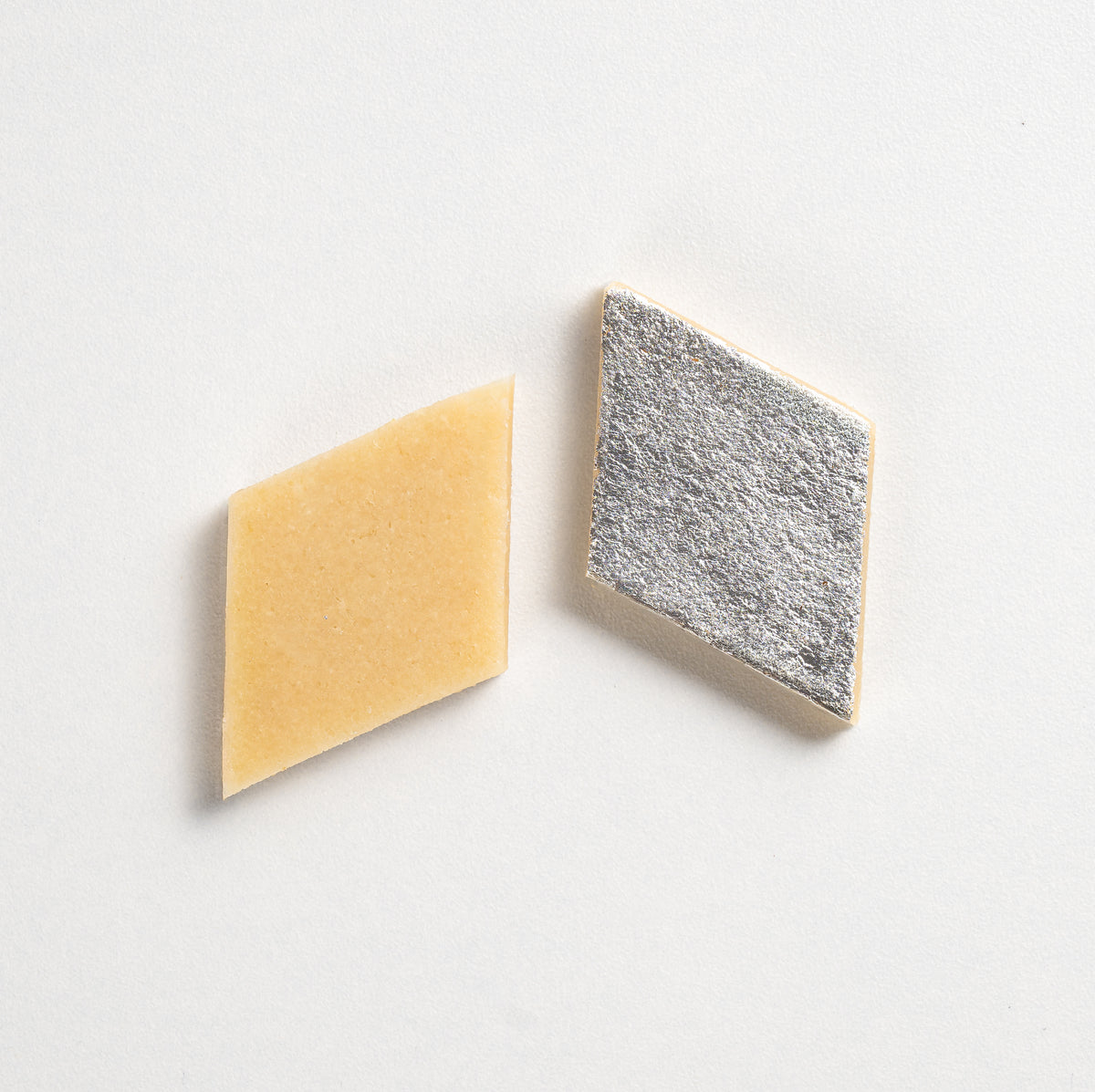 Two geometrically shaped tiles, one yellow and one textured gray, on a light gray background.