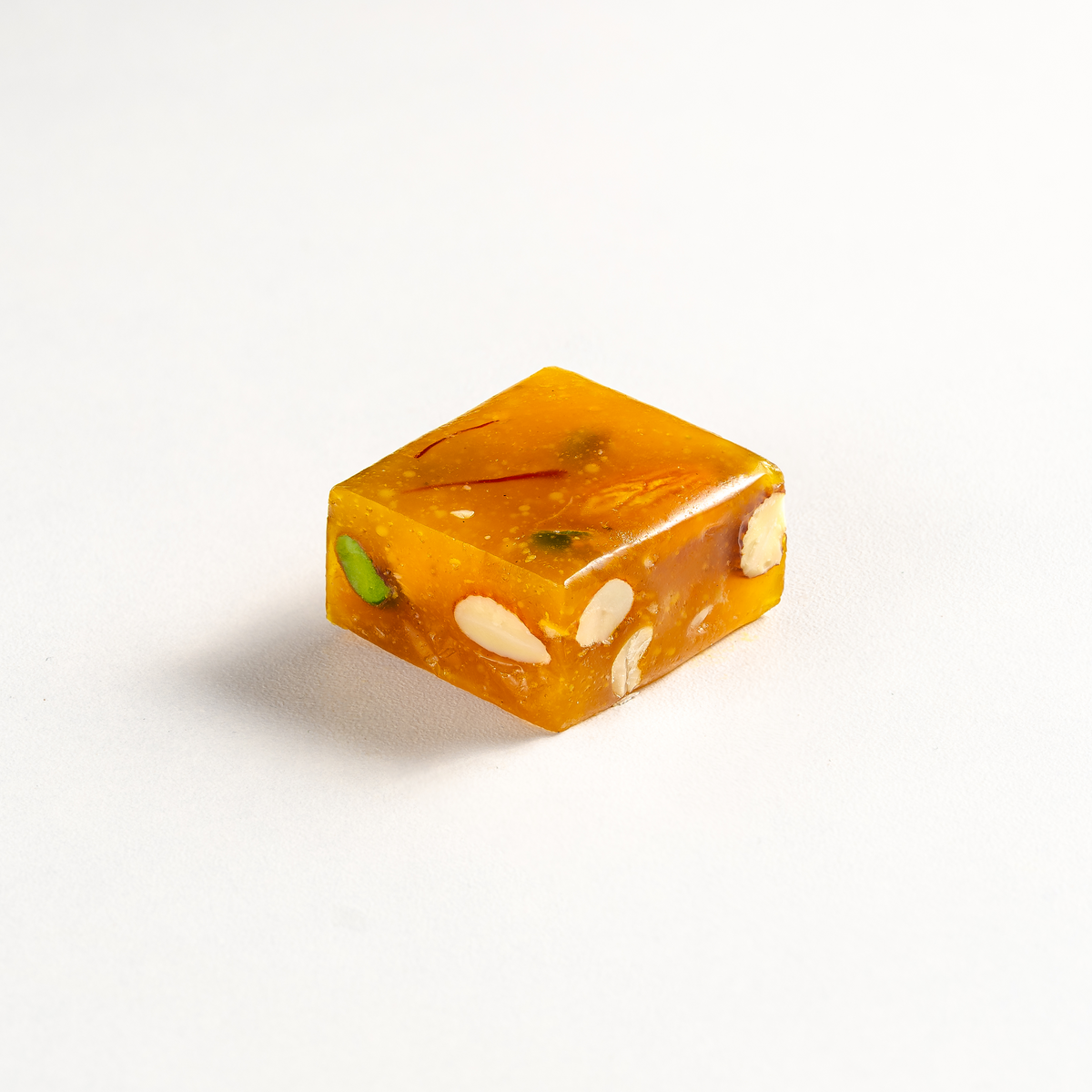 Square piece of orange candy with nuts on a white background