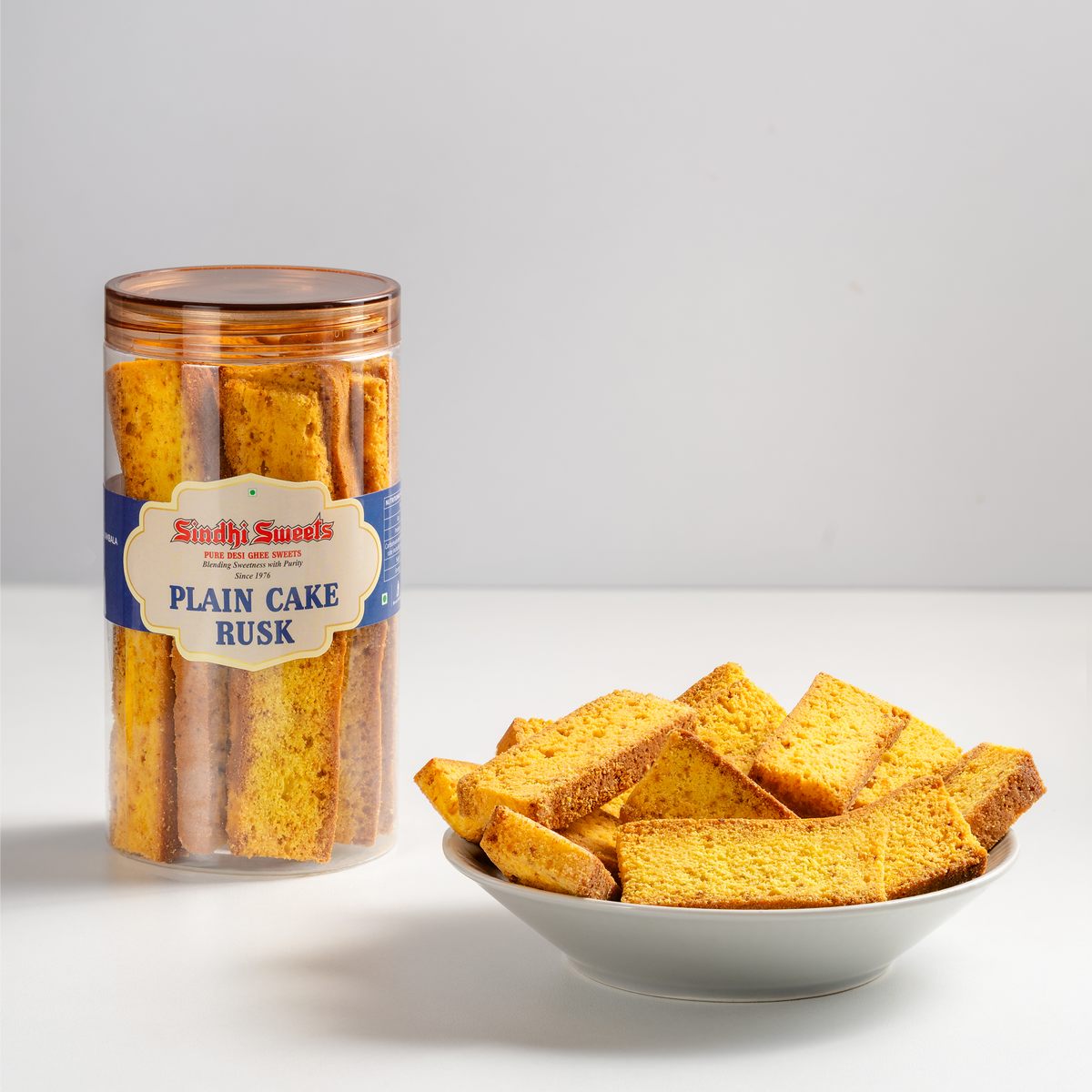 Jar of plain cake rusk and a bowl of rusk on a light gray background